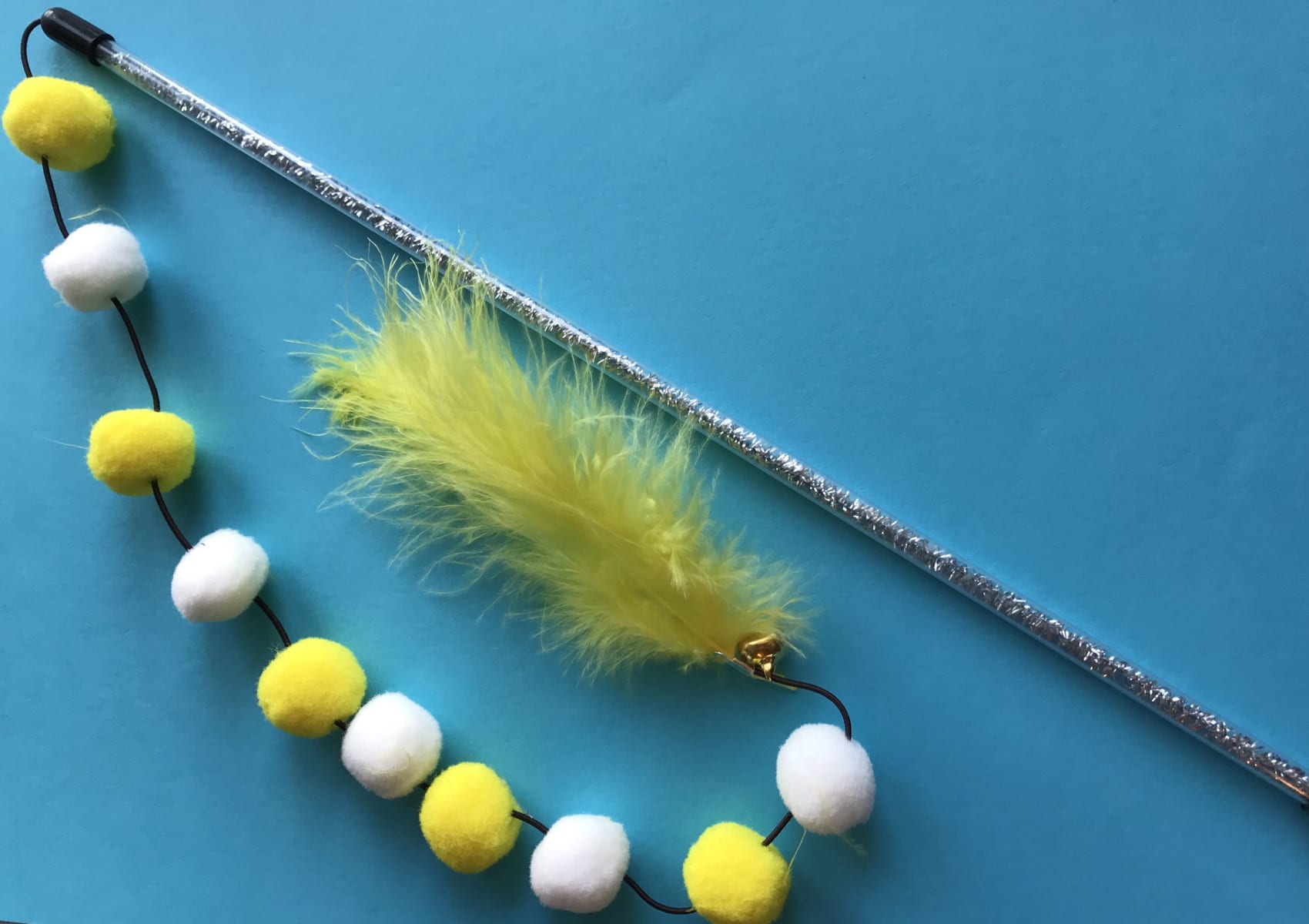 Yellow pompom toy for your cat with fluffy balls and feathers on a stick